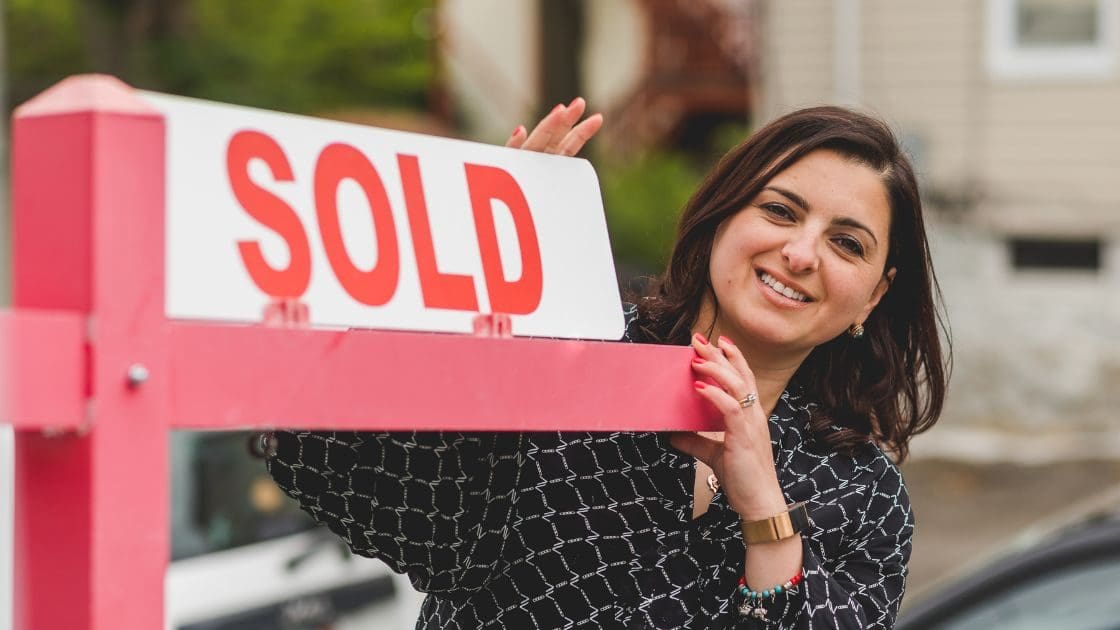 A real estate agent changing the for sale sign to sold.