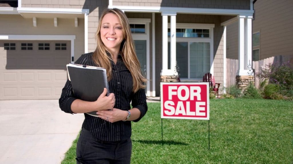 A home seller placing a for sale sign in her property.