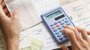 A person looking at a document with a calculator in hand