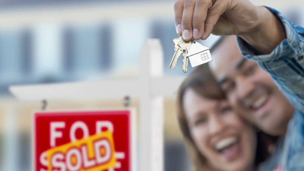 A happy couple holding the keys to their new home after buying a house in Canada